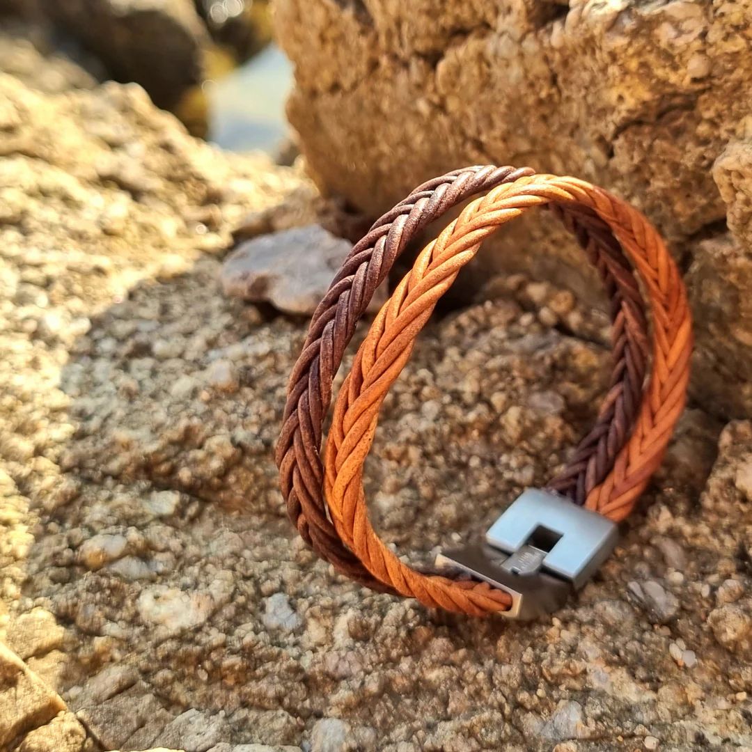Gevlochten leren armband bruin met twee koorden, op rotsen sieraden display